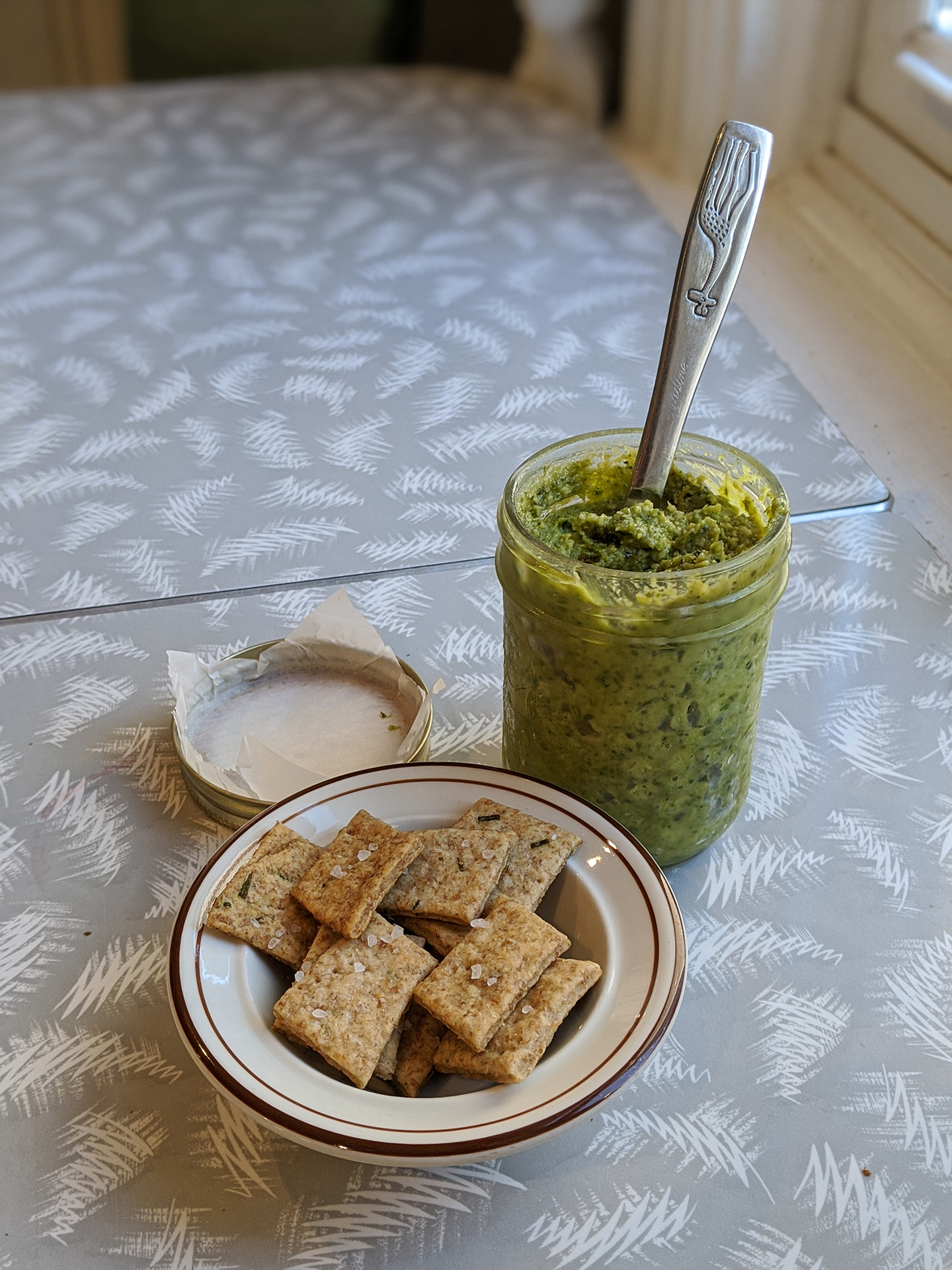 jar of pesto with bowl of crackers