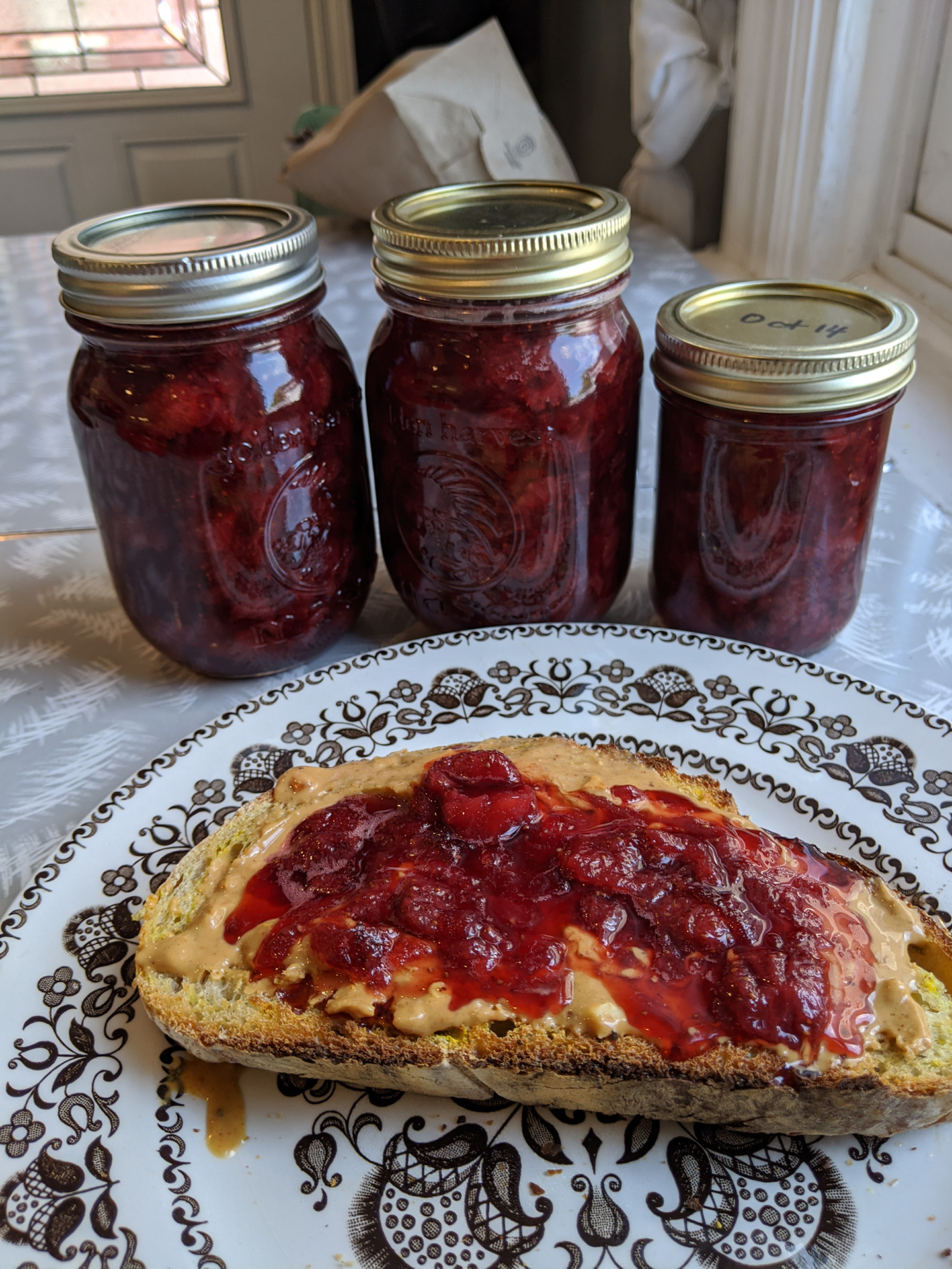 jars of strawberry of jam with toast on plate
