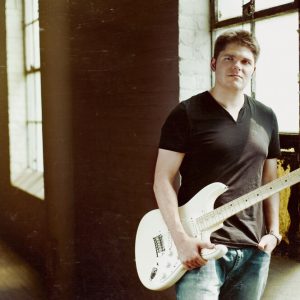 Andre Bisson Andre Bisson holding a guitar near a window