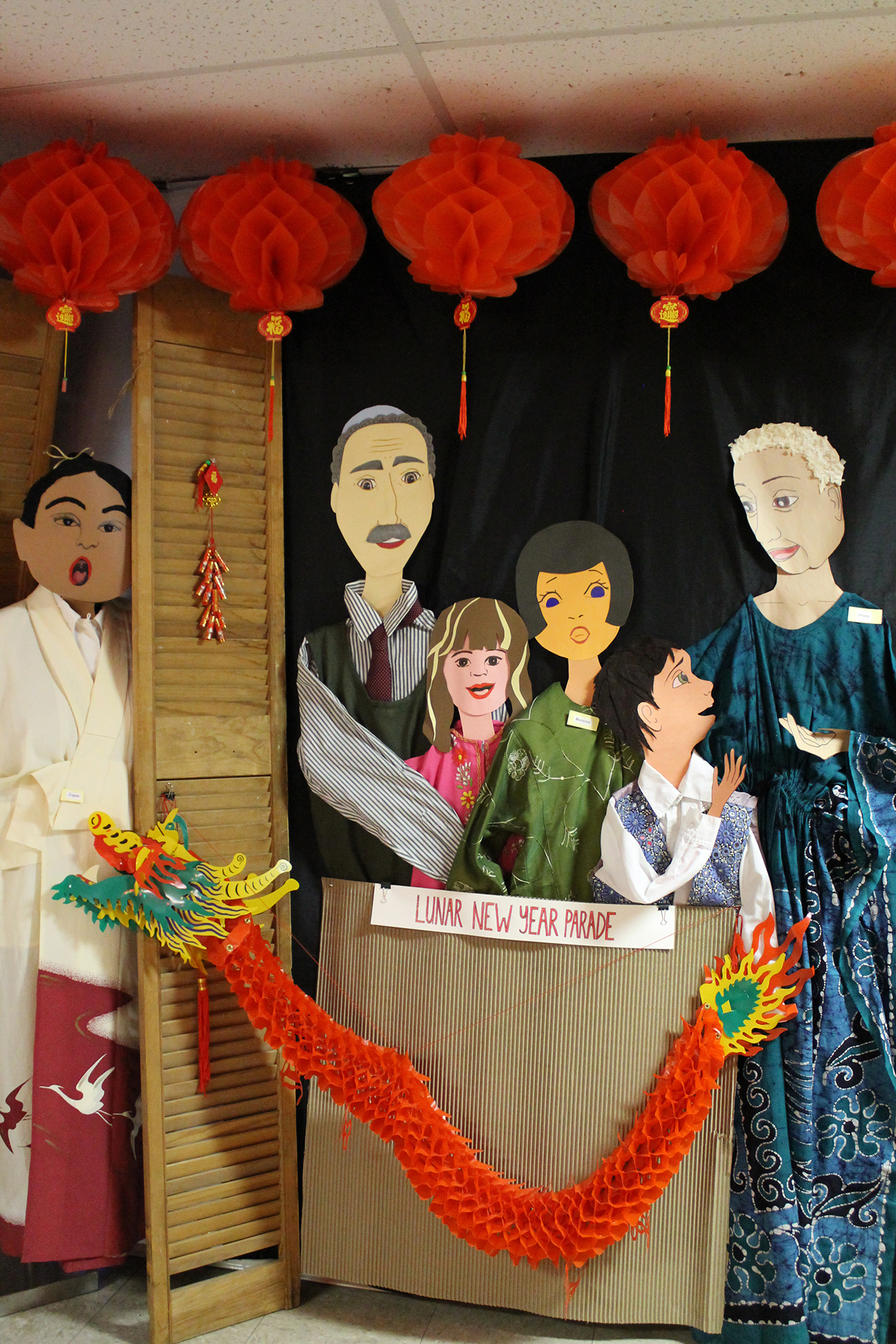 Museum display of paper people celebrating Lunar new year, with lantern and dragon decorations