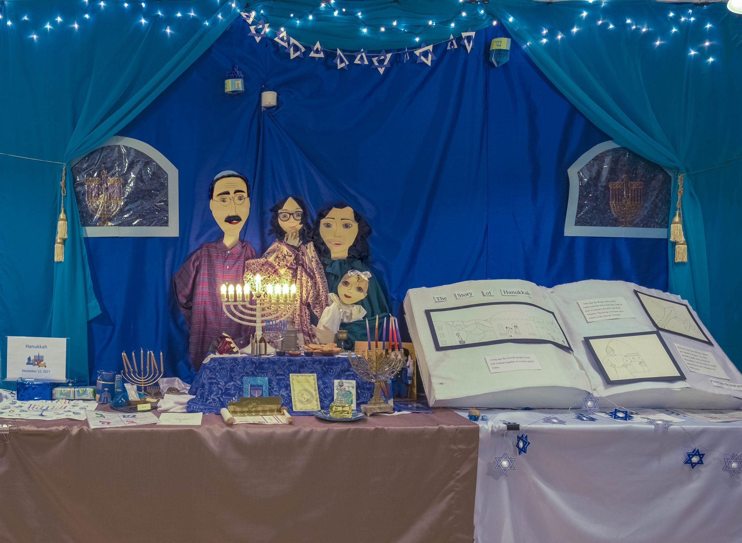 Museum display showcasing a family and Hanukkah celebration including large book