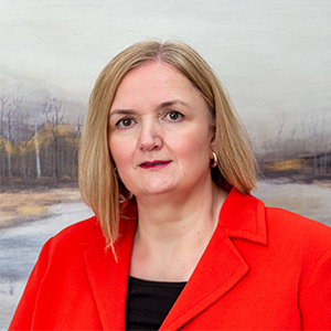 Headshot of Nancy Rowland, wearing red blazer