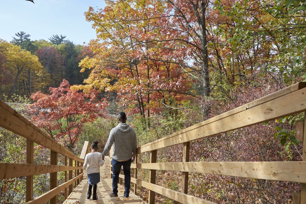 father and daughter hiking on staircase along boardwalk fall