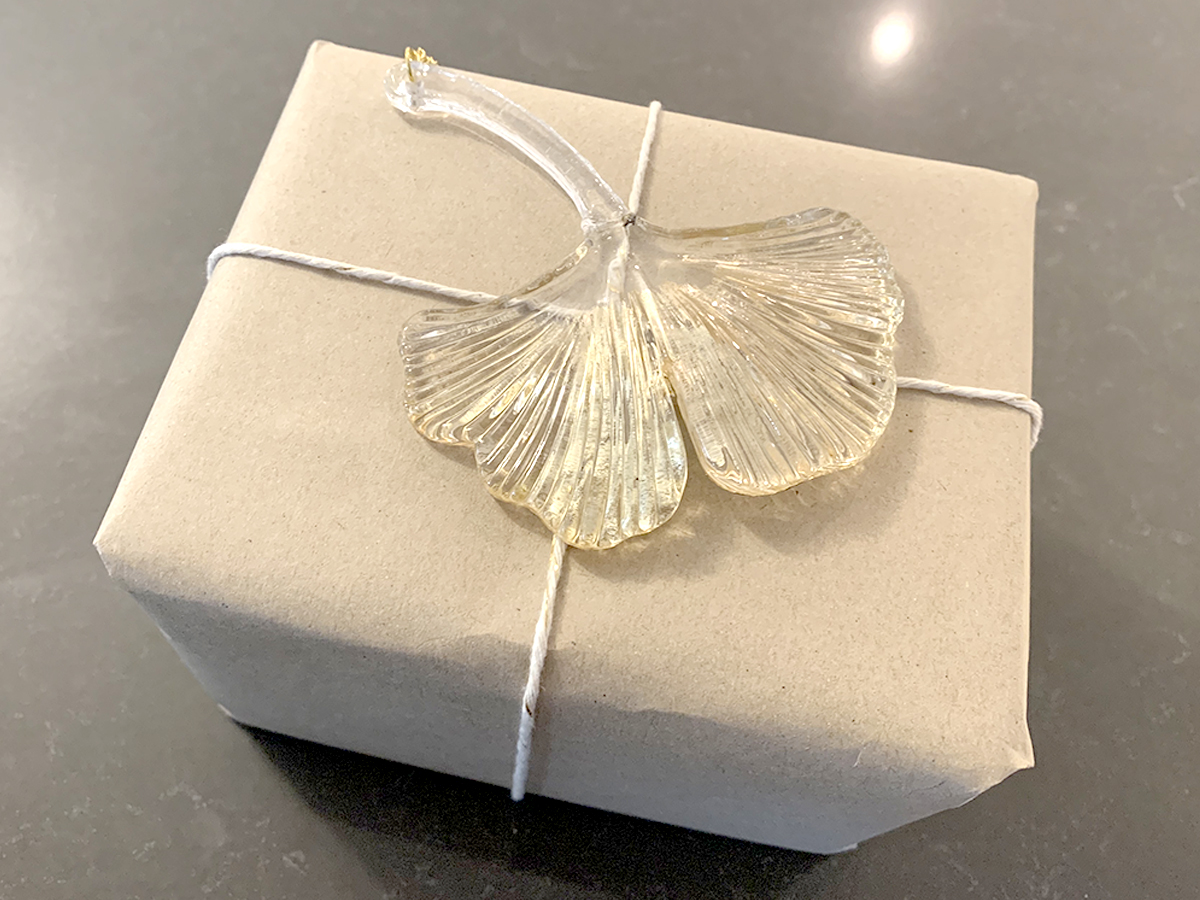 box wrapped in craft paper topped with a glass ginkgo leaf