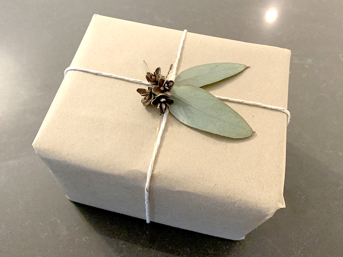 box wrapped in craft paper topped with dried leaves and pinecones