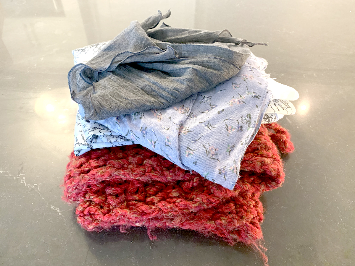 three different pieces of fabric (in red, white patterrned and grey) folded in a stack