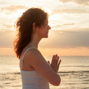 louise-vien Louise standing by the water with her arms held up and palms pressed together close to her chest