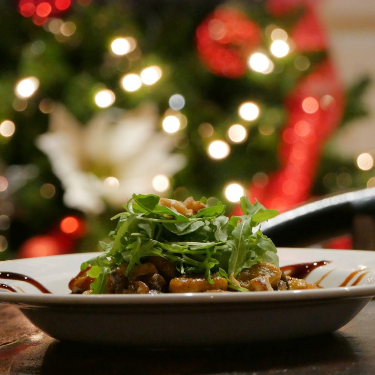 close up view of gnocchi with a christmas tree in the backgrounf
