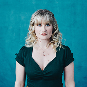 Shannon Butcher in dress standing against blue background