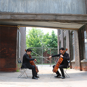 two cellists playing in alleyway